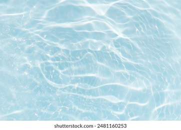 Bluewater waves on the surface ripples blurred. Defocus blurred transparent blue colored clear calm water surface texture with splash and bubbles. Water waves with shining pattern texture background.