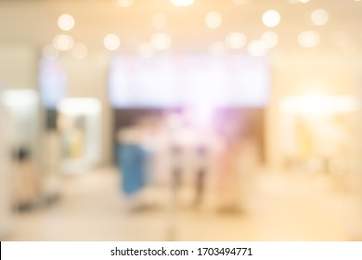 Blurred background with bokeh light in luxury fashion shopping mall with shop window and display modern model from stores with women and men customer walking in walkway hallway in department