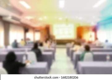 Blurred business people in convention room with large screen in front